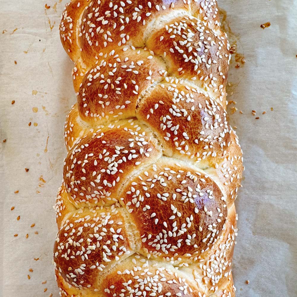 braided baked challah loaf sprinkled with sesame seeds