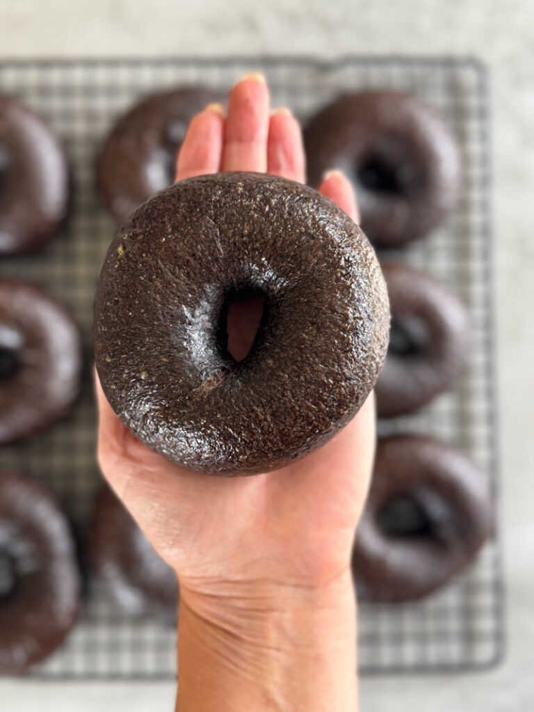 A brown pumpernickel bagel on a woman's palm
