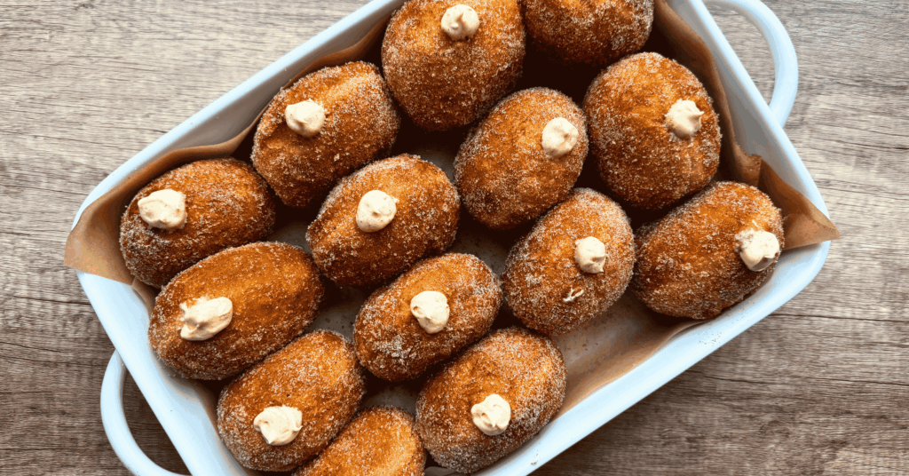 &bull; Pumpkin sourdough donuts rolled in pumpkin spice sugar stacked in a pan